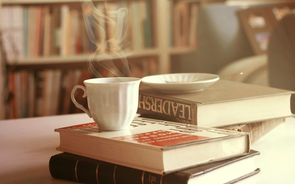 Drink Coffee From White Mug With Glasses And Book On Table