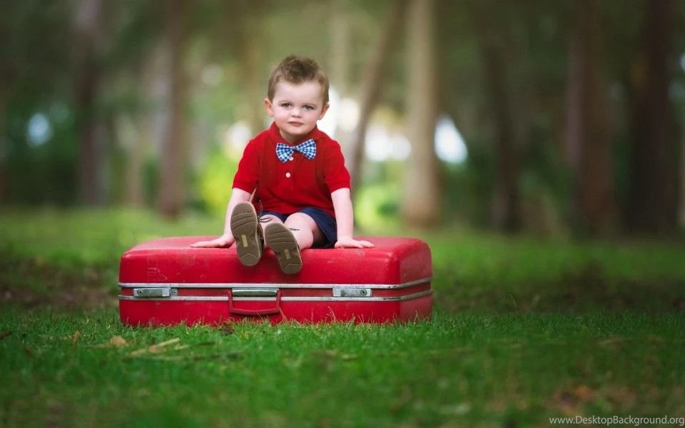 Cute Baby Boy Sitting On Red Suitcase Wallpaper.jpg
