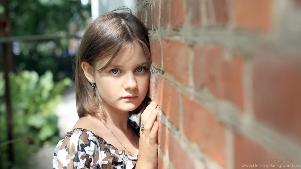 A Beautiful Girl With Blue Eyes Near A Brick Wall