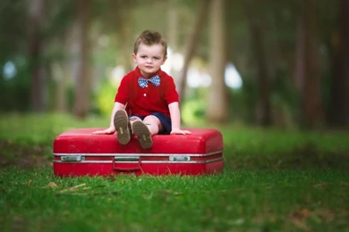 Cute Baby Boy Sitting On Red Suitcase Wallpaper.jpg