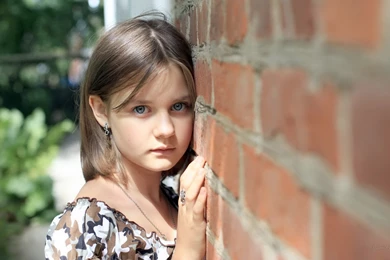 A Beautiful Girl With Blue Eyes Near A Brick Wall